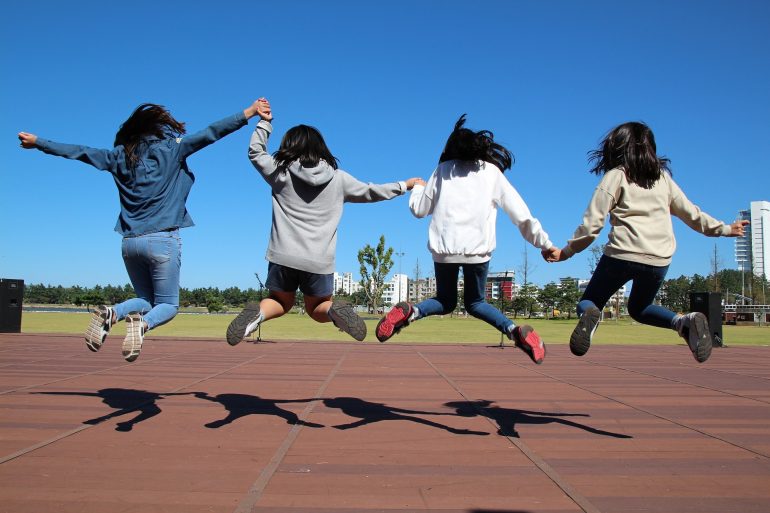 Kids holding hands jumping for joy